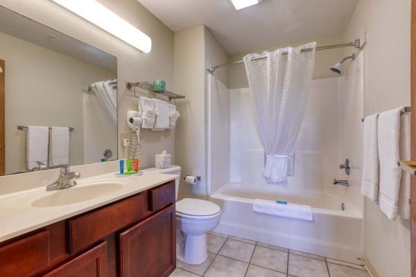 A clean bathroom with a sink, mirror, toiletries, towel rack, and a bathtub with a shower curtain.