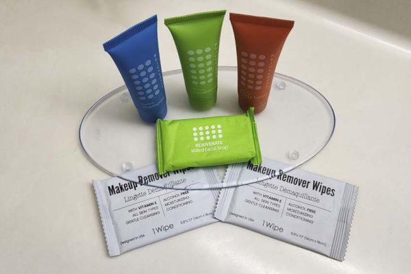 Hotel toiletries include shampoo, conditioner, lotion, soap, and makeup remover wipes on a countertop.