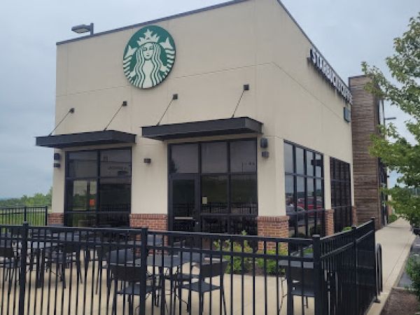 The image shows a Starbucks store with outdoor seating and a visible logo on the building.