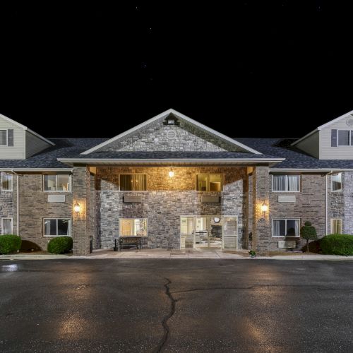 A well-lit, two-story brick building at night, possibly a hotel or inn, with a centered entrance and a dark sky background.
